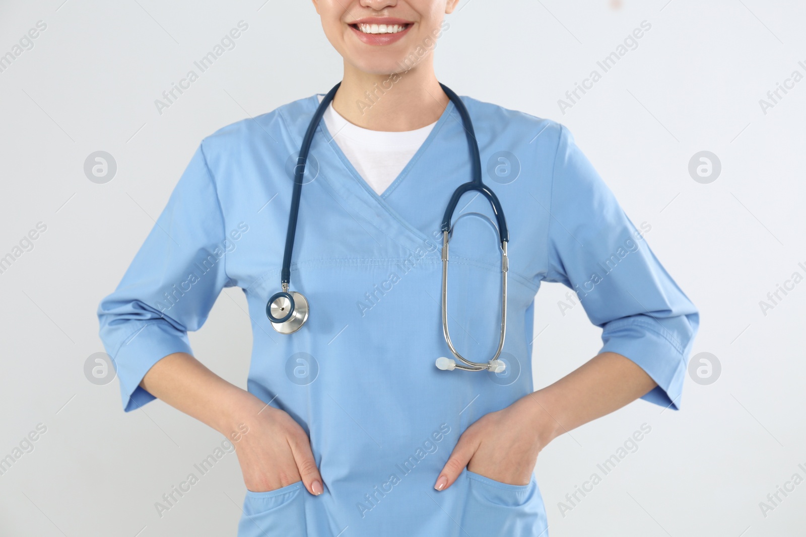 Photo of Young doctor with stethoscope on light background, closeup