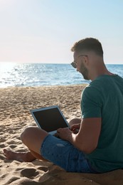 Photo of Man working with modern laptop on beach