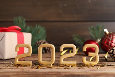 Photo of Number 2023 and festive decor on wooden table, space for text. Happy New Year