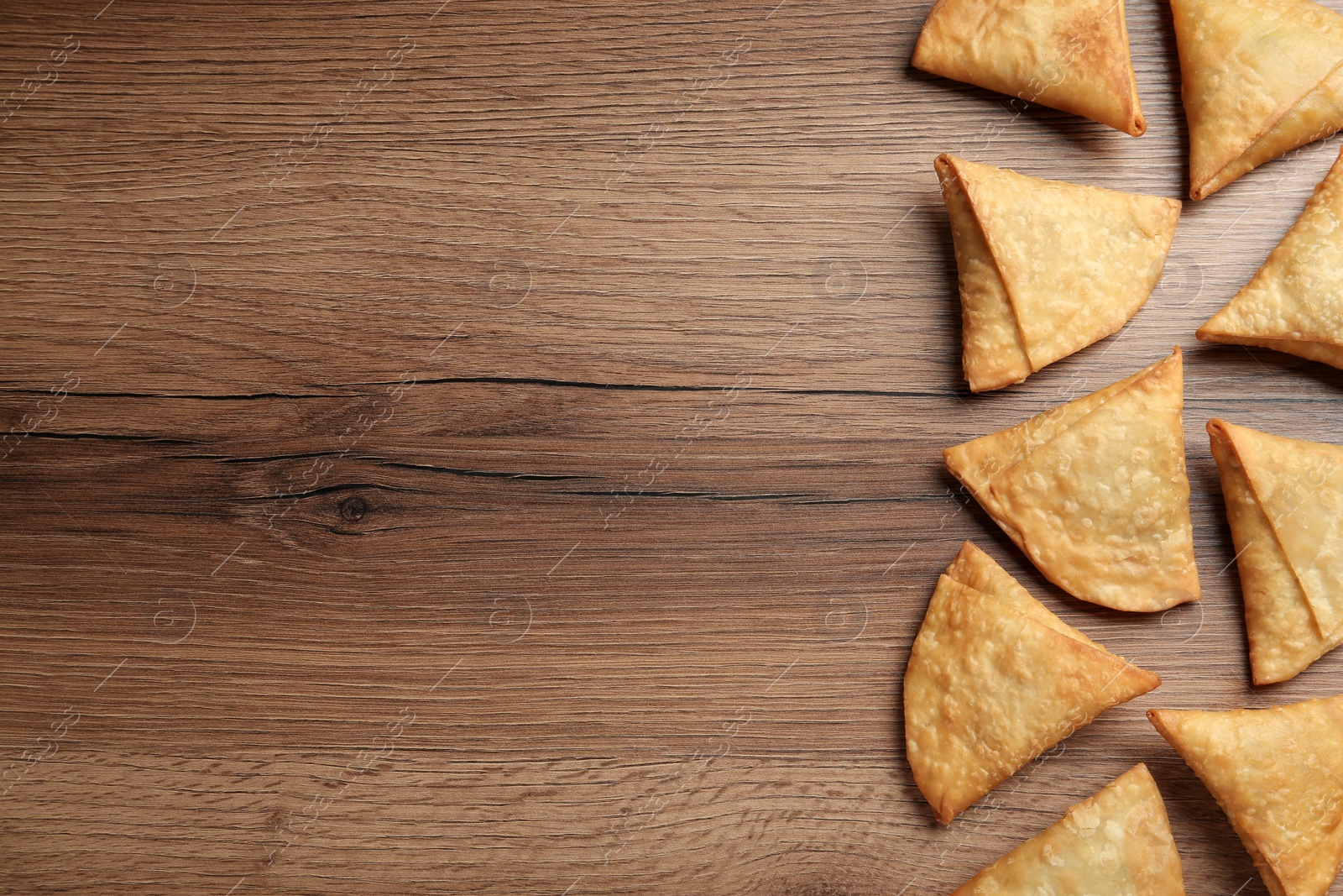 Photo of Fresh delicious crispy samosas on wooden table, flat lay. Space for text