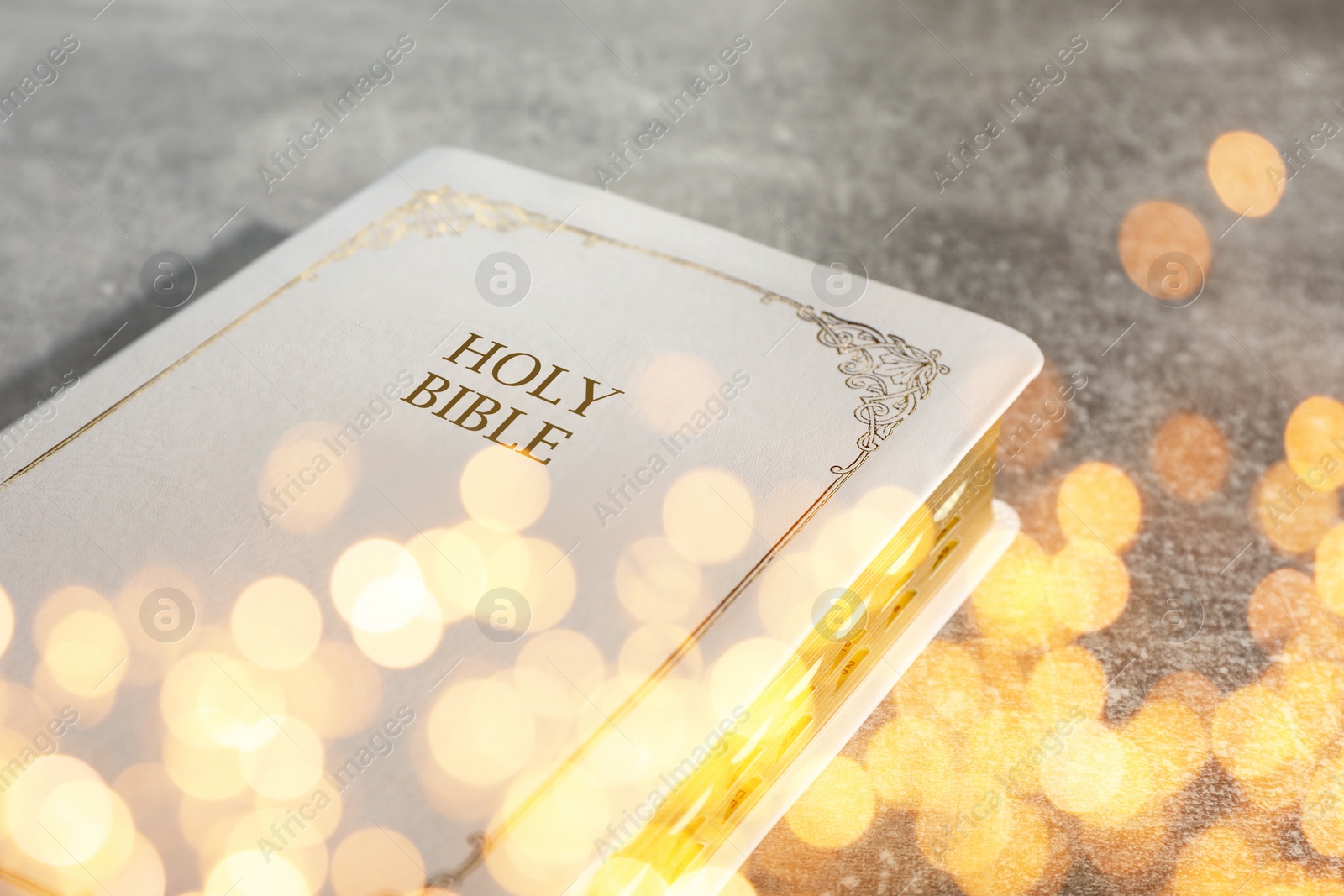 Image of Holy Bible on stone table, bokeh effect