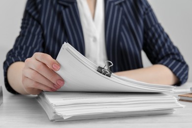 Photo of Woman reading documents at white wooden table in office, closeup