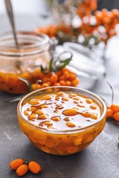 Delicious sea buckthorn jam and fresh berries on grey table