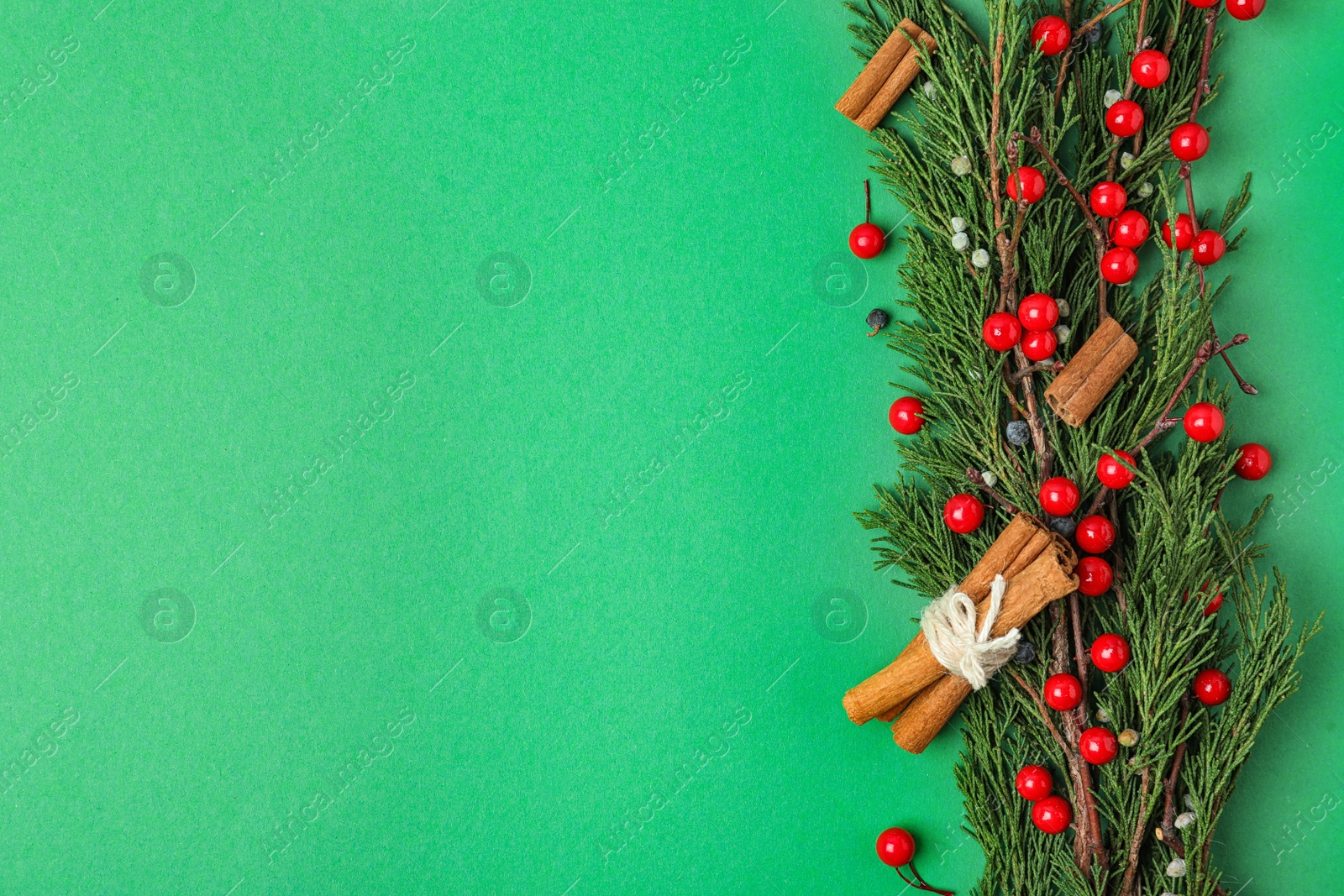 Photo of Christmas flat lay composition with conifer branches and berries on green background, space for text. Winter holidays