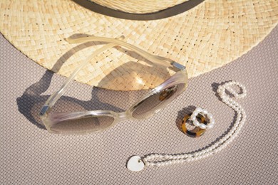 Photo of Stylish hat, sunglasses and jewelry on grey surface, above view