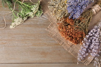 Photo of Different herbs and burlap fabric on wooden table, flat lay. Space for text