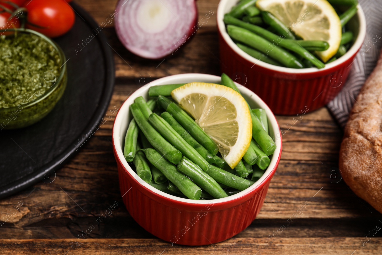 Photo of Raw green beans with lemon on wooden table, closeup