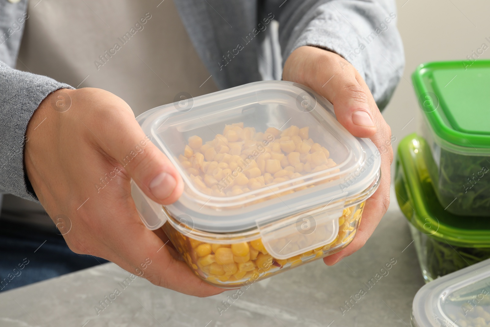 Photo of Man holding glass container with tasty corn kernels, closeup. Food storage