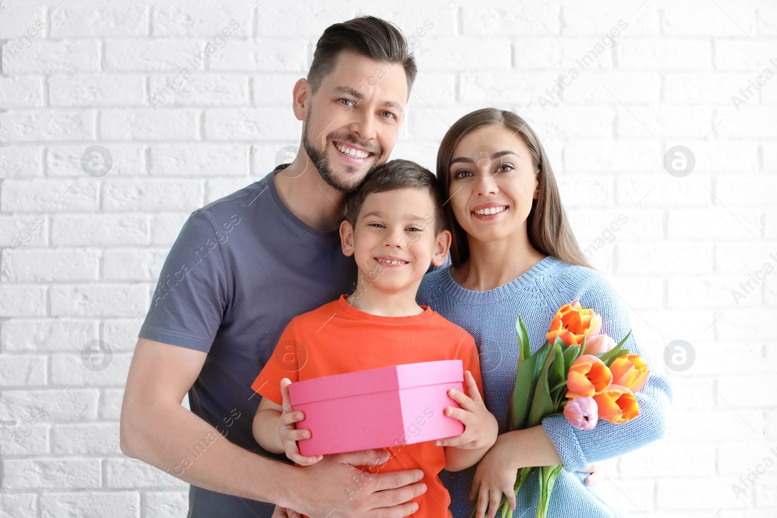 Photo of Portrait of happy family with gifts on brick wall background. Mother's day celebration