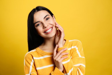 Photo of Portrait of happy young woman with beautiful black hair and charming smile on yellow background