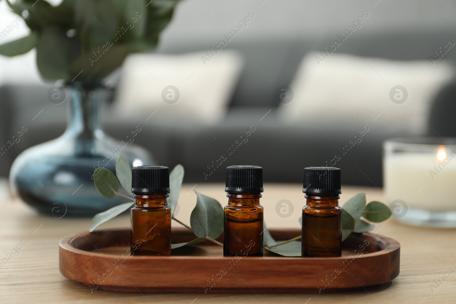 Photo of Aromatherapy. Bottles of essential oil and eucalyptus leaves on wooden table