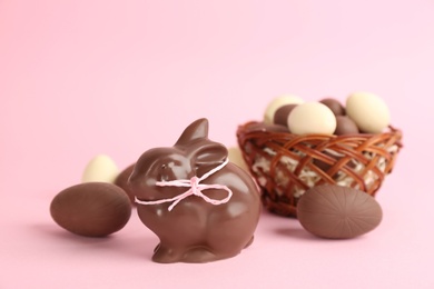 Photo of Chocolate Easter bunny and eggs on pink background. Space for text