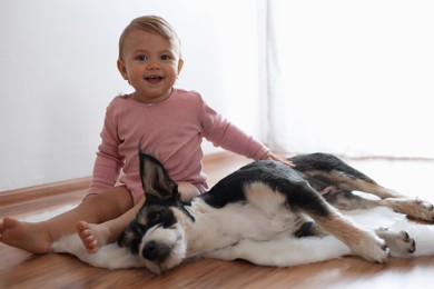 Photo of Adorable baby and cute dog on faux fur rug indoors