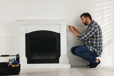 Photo of Man with screwdriver installing electric fireplace in room