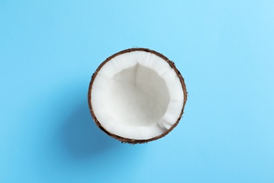 Half of coconut on color background, top view