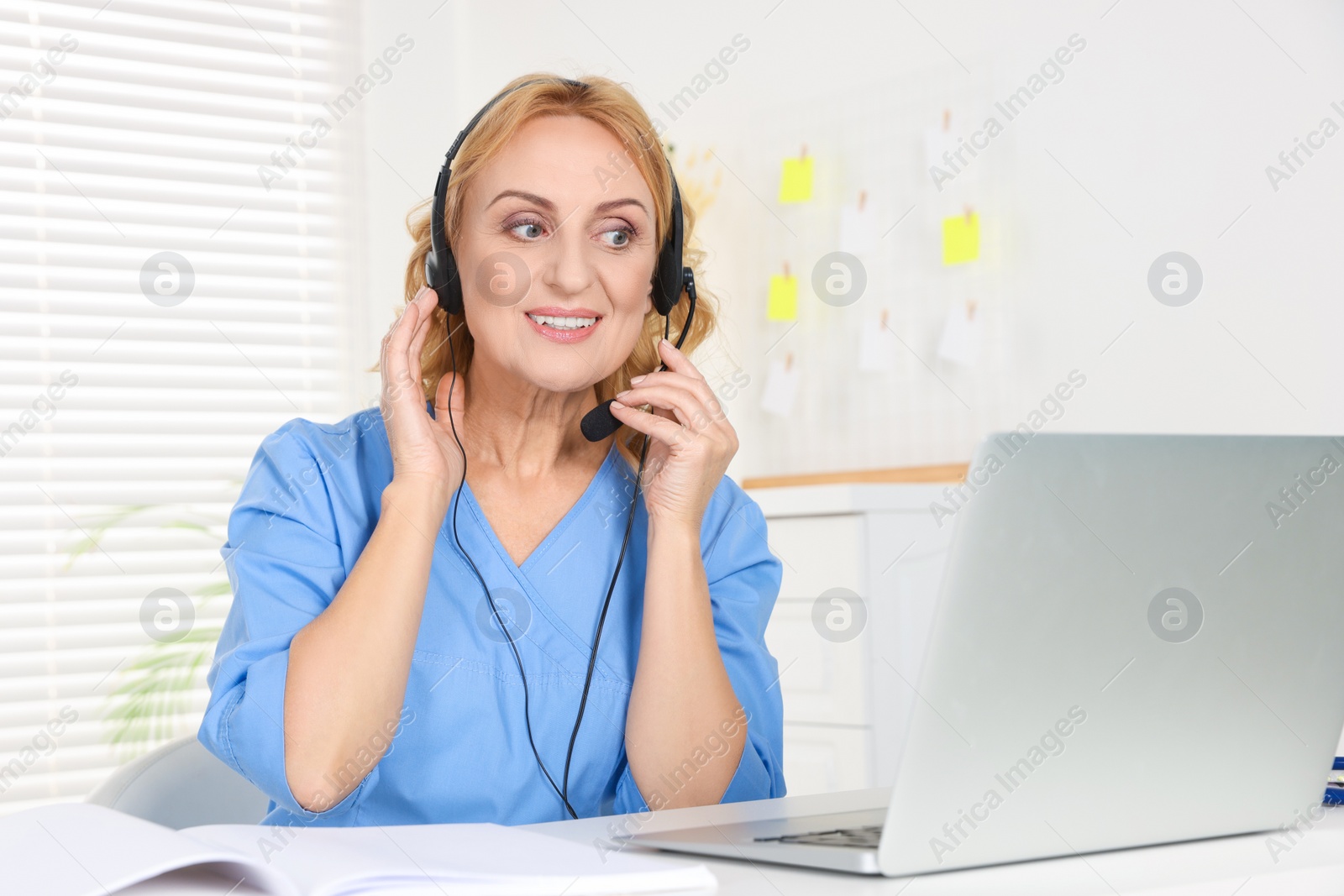 Photo of Doctor with laptop and headphones consulting patient in clinic. Online medicine concept