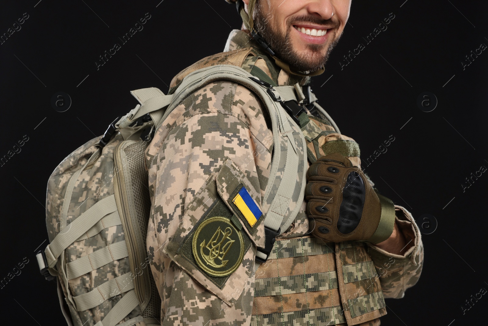 Photo of Soldier in Ukrainian military uniform with backpack on black background, closeup