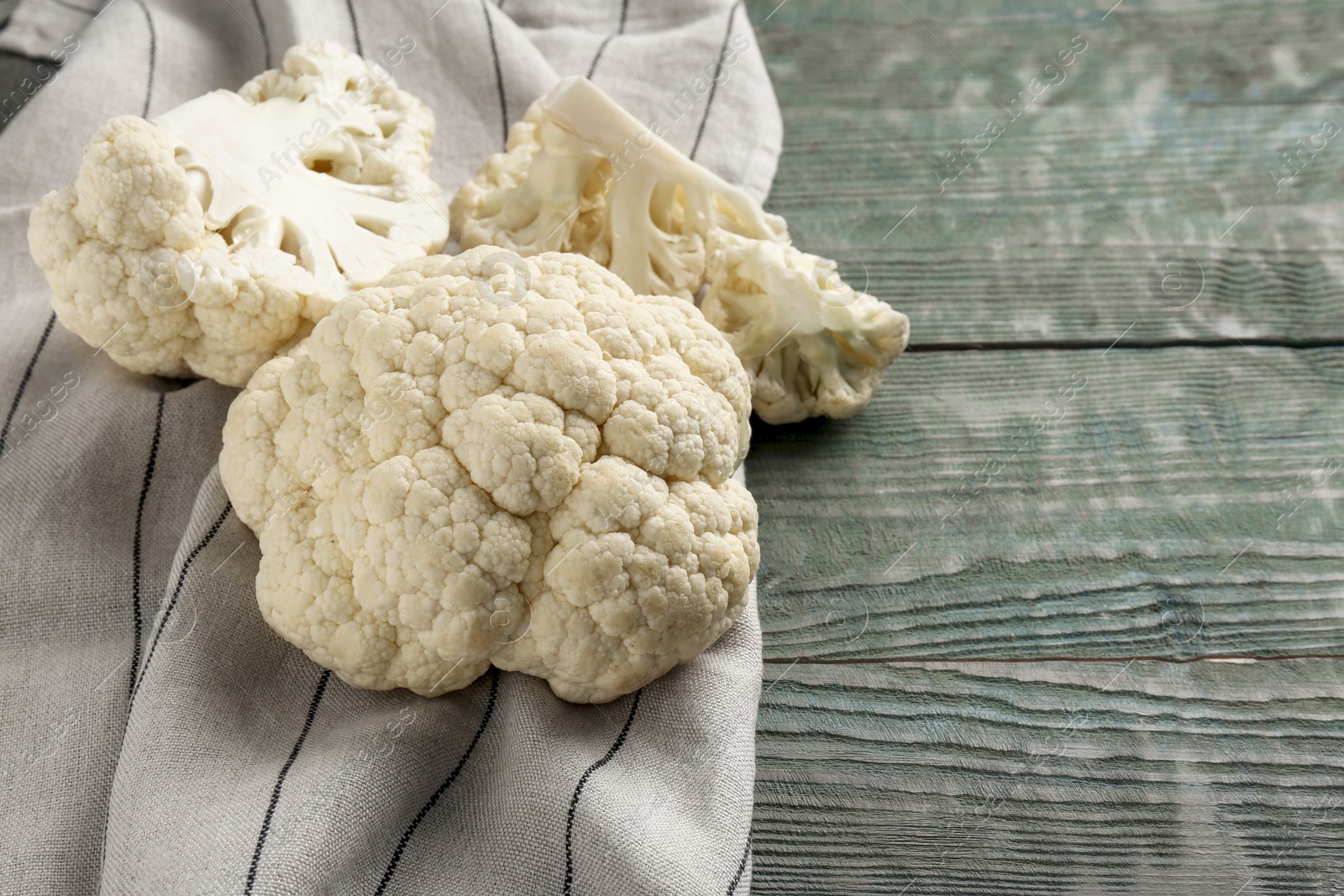 Photo of Fresh raw cauliflower on light blue wooden table. Space for text