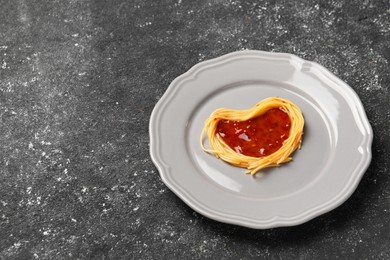 Photo of Heart made with spaghetti and sauce on black table. Space for text