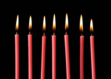 Burning red candles on black background, closeup