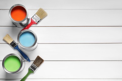 Photo of Cans of red, light blue and green paints on white wooden table, flat lay. Space for text