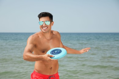 Photo of Happy man throwing flying disk at beach on sunny day