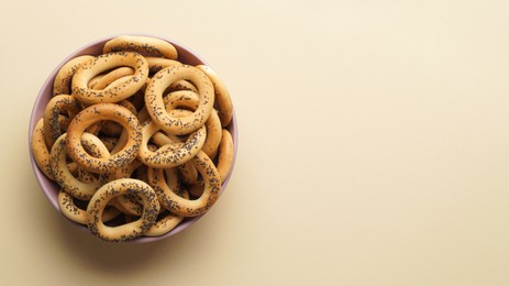 Photo of Bowl with delicious ring shaped Sushki (dry bagels) on beige background, top view. Space for text