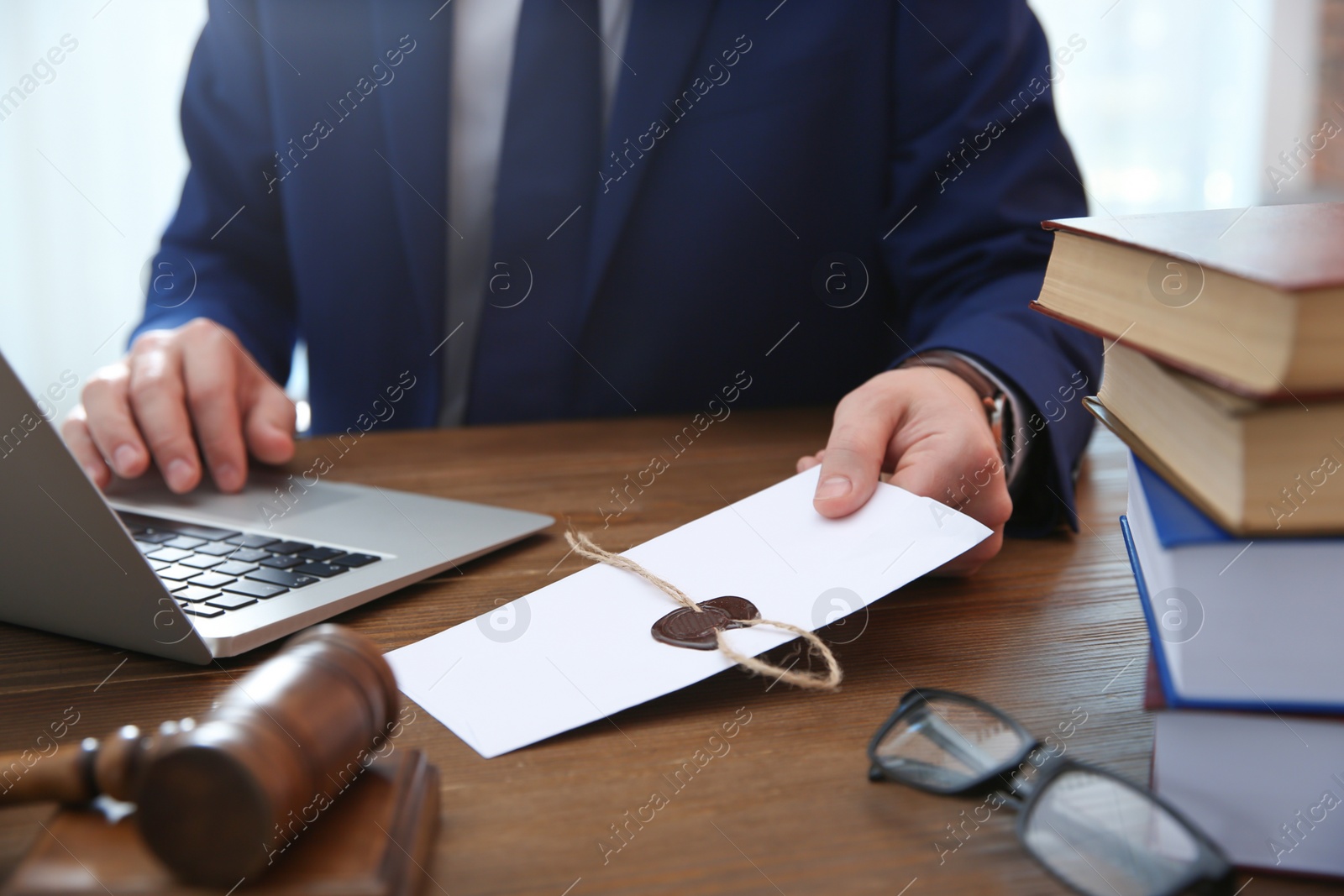 Photo of Notary with envelope at table, closeup. Law and justice concept