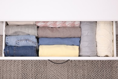 Photo of Open drawer with folded clothes indoors, top view. Vertical storage