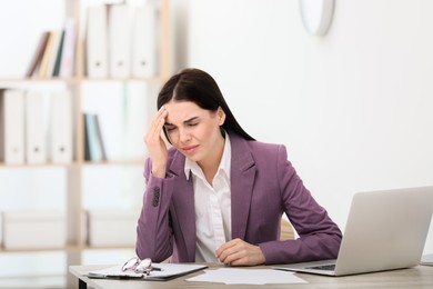 Woman suffering from migraine at workplace in office