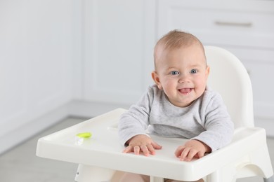 Cute little baby in high chair at home