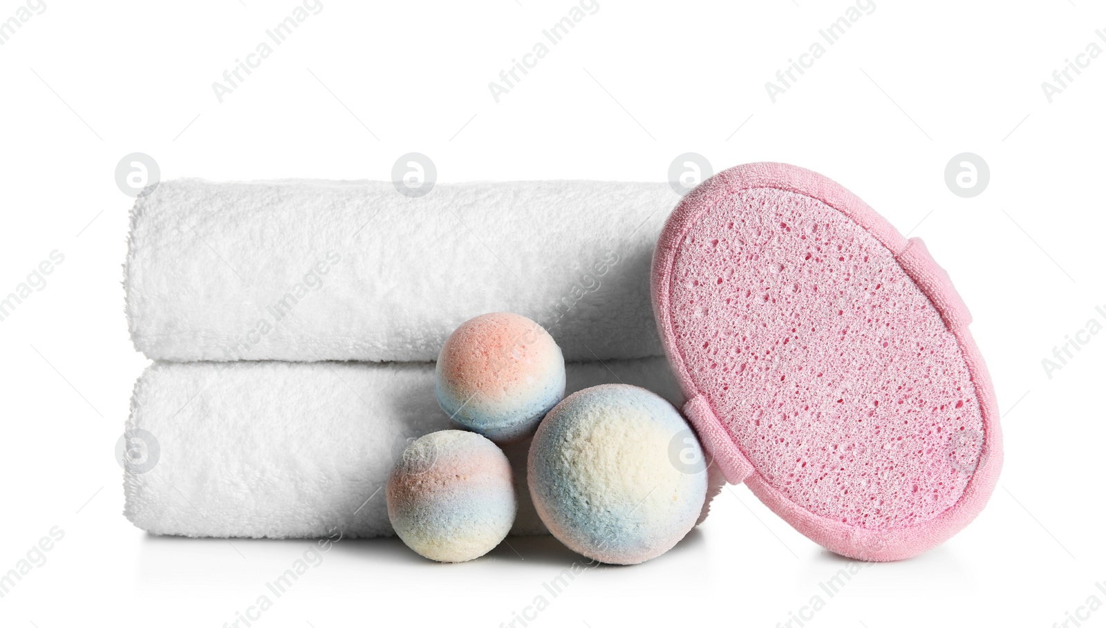 Photo of Stack of clean soft towels, bath bombs and sponge on white background