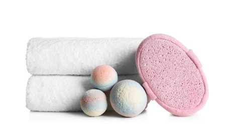 Stack of clean soft towels, bath bombs and sponge on white background