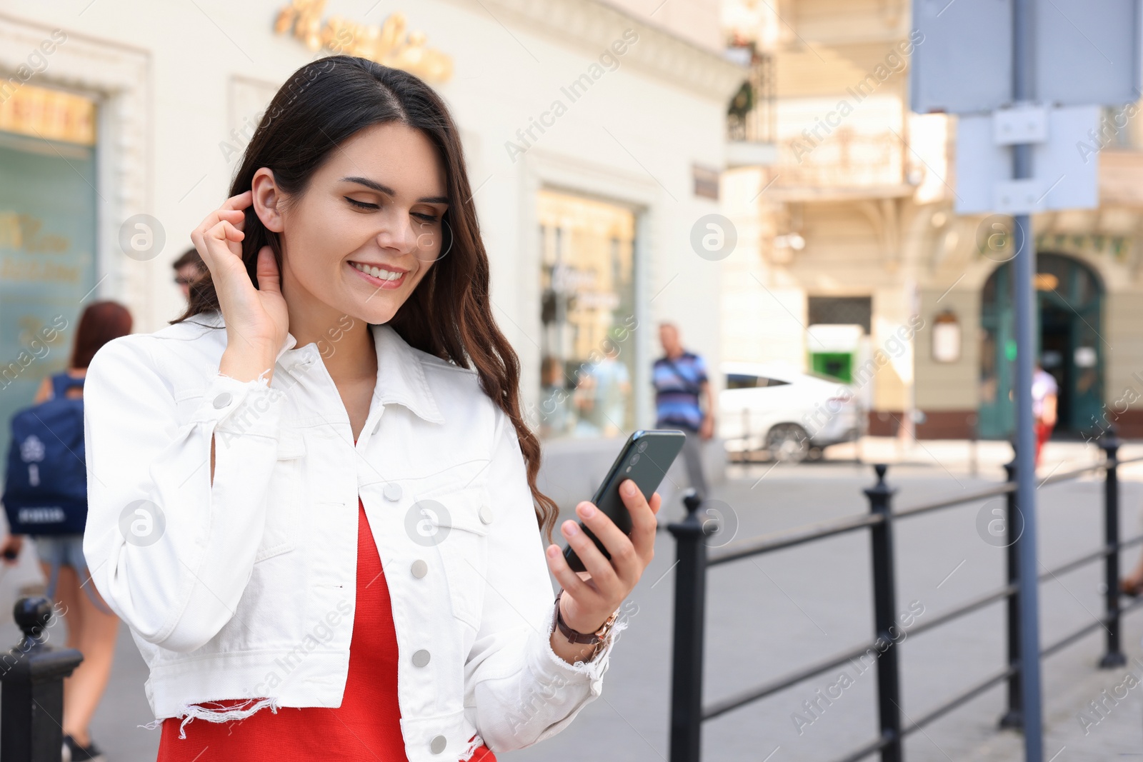 Photo of Beautiful young woman with smartphone on city street