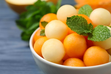 Melon balls and mint in bowl on blue wooden table, closeup