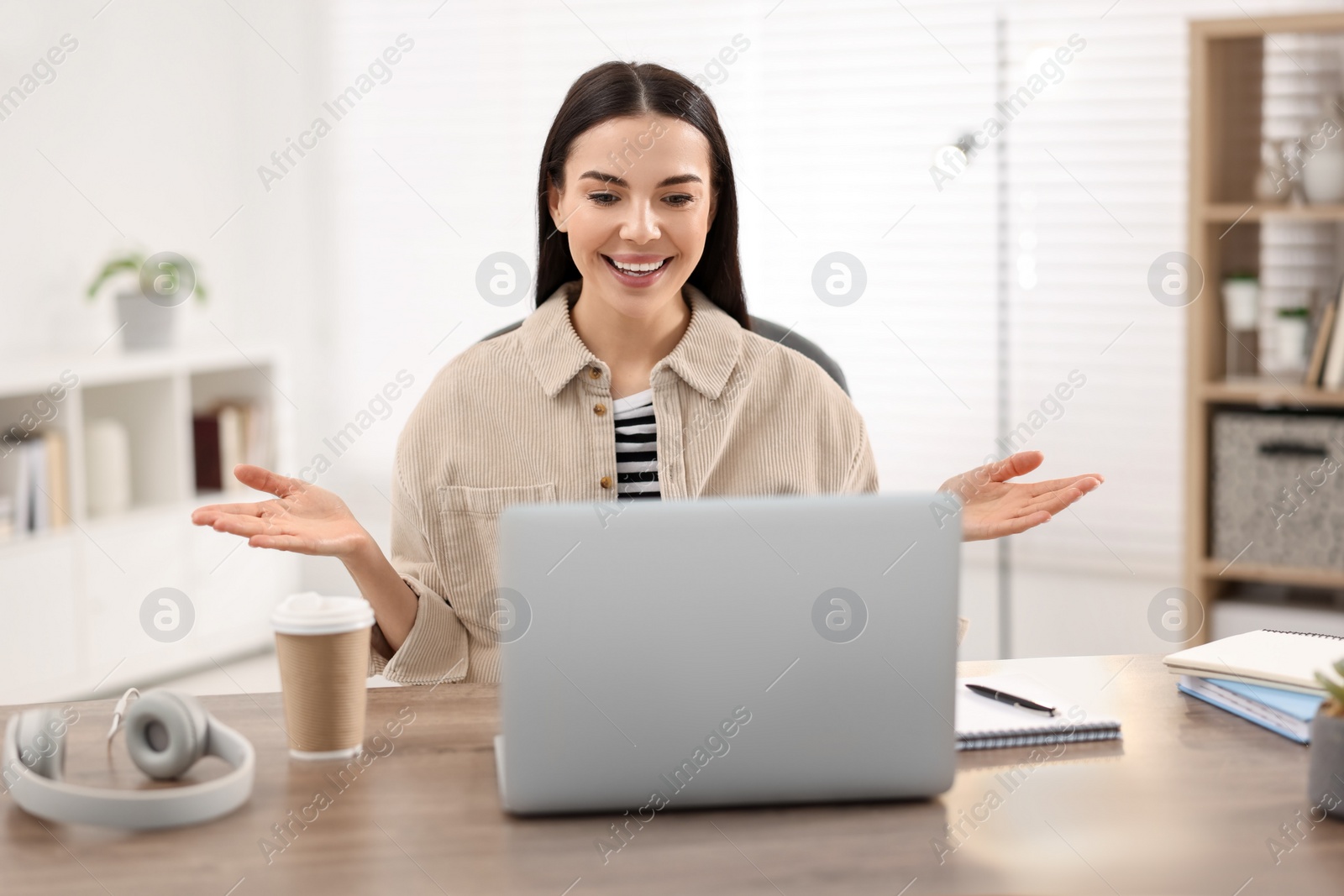 Photo of Young woman using video chat during webinar at table in room