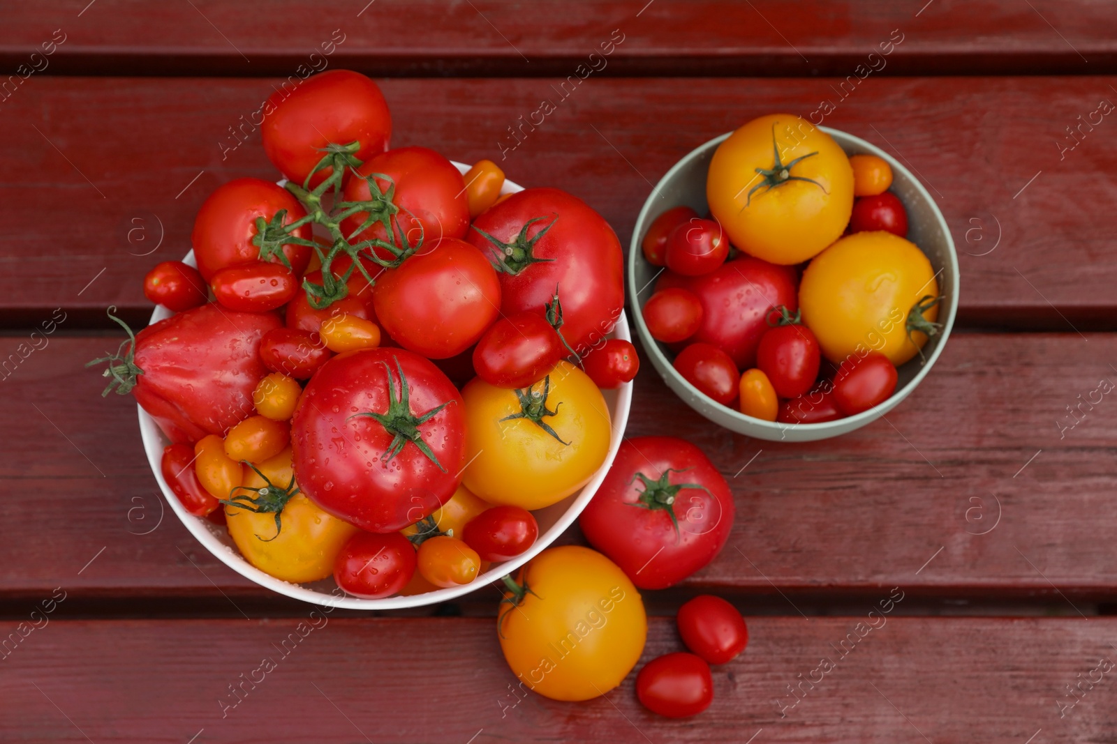 Photo of Bowls with fresh tomatoes on wooden table, flat lay