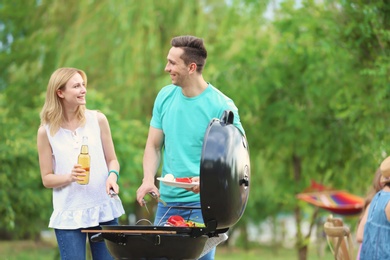 Photo of Young people having barbecue with modern grill outdoors