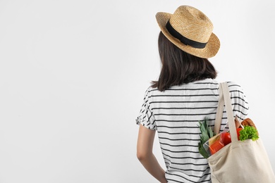 Photo of Woman holding shopping bag with fresh vegetables on white background