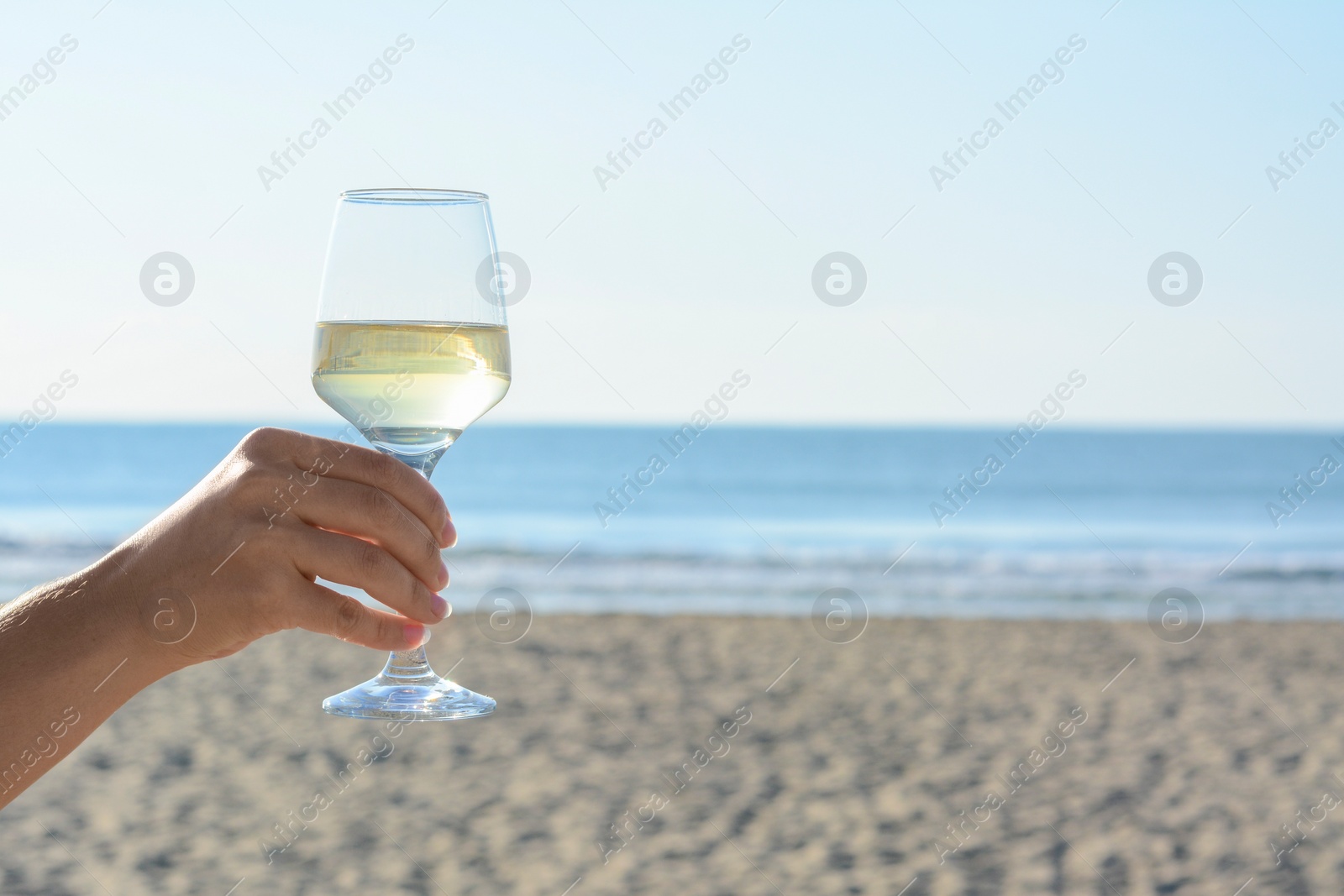 Photo of Woman with glass of tasty wine near sea, closeup. Space for text