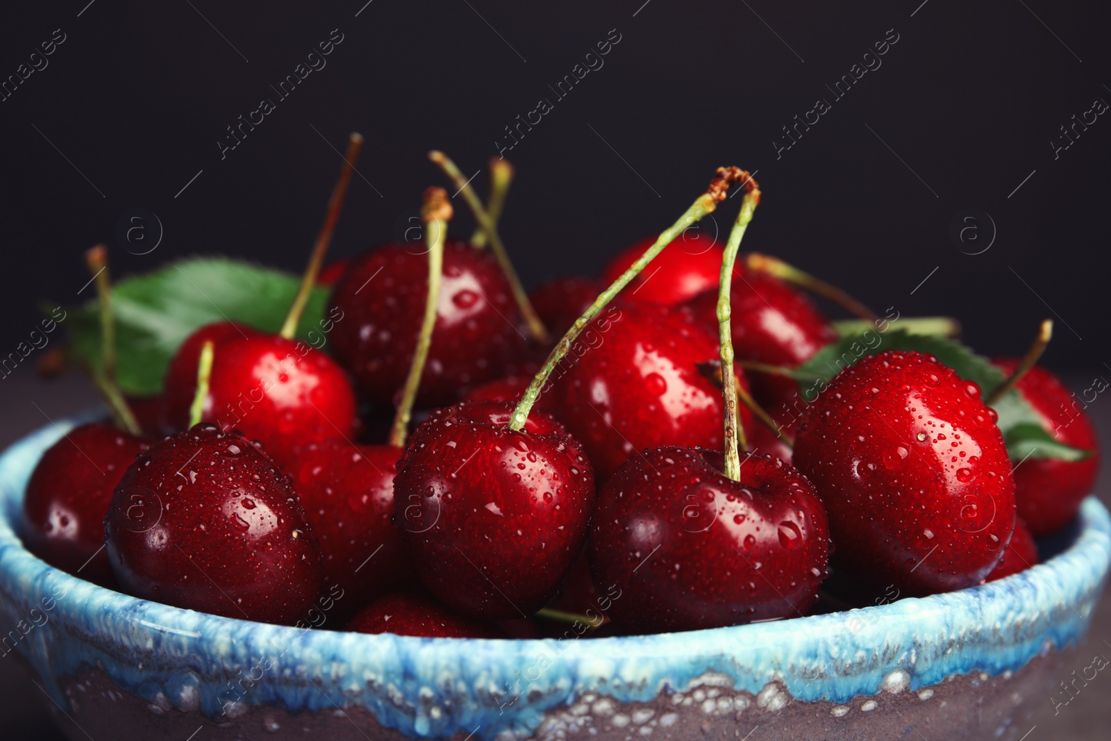 Photo of Bowl with sweet cherries on dark background, closeup