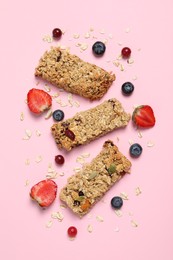 Photo of Tasty granola bars and ingredients on pink background, flat lay