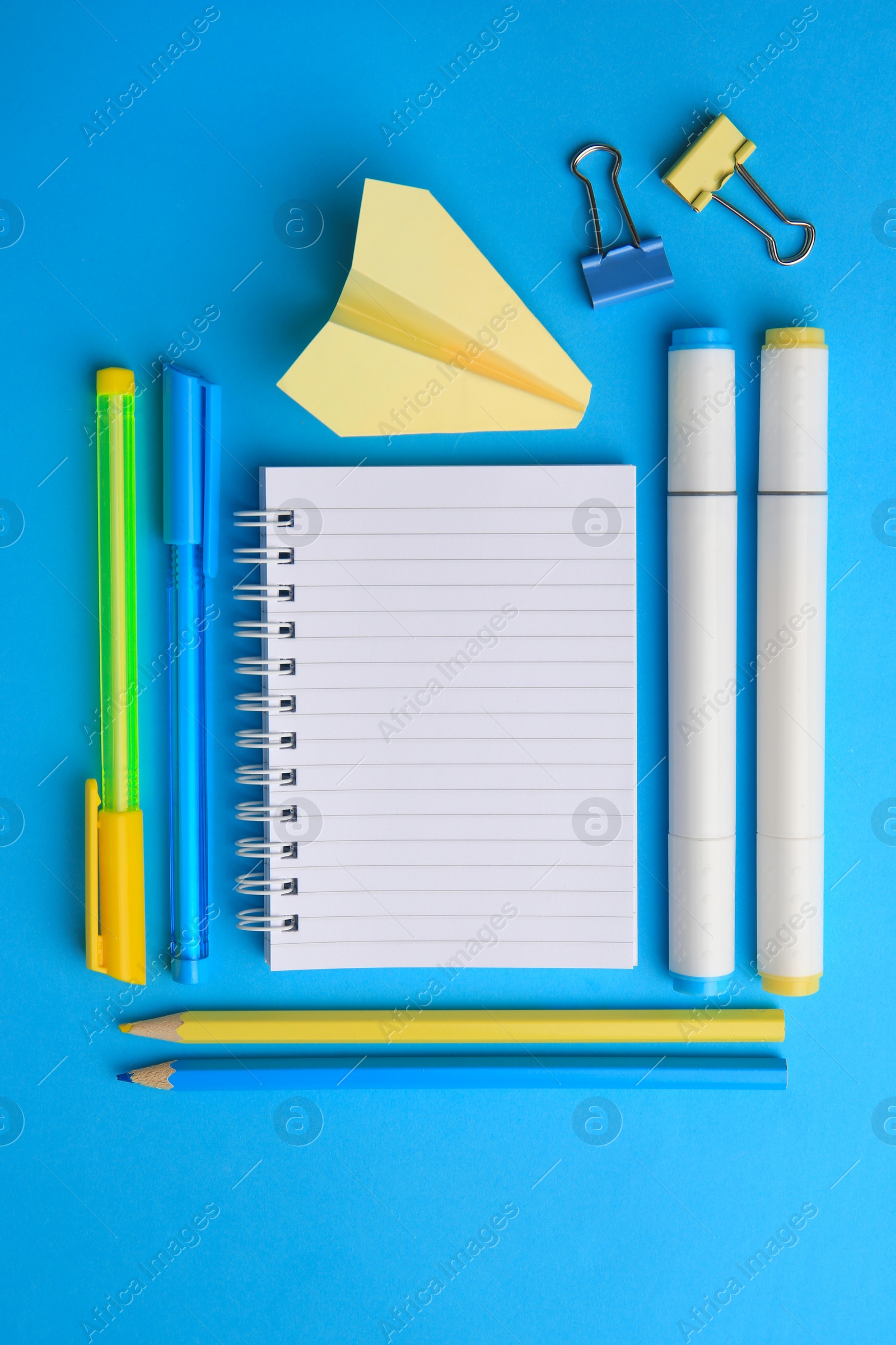 Photo of Paper plane and different school stationery on light blue background, flat lay with space for text. Back to school