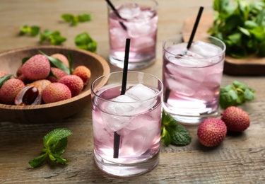 Photo of Delicious lychee cocktails and fresh fruits on wooden table