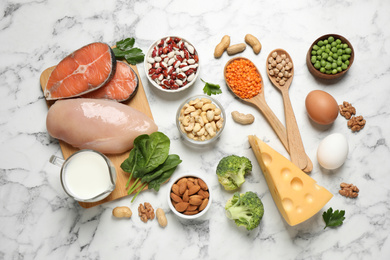 Photo of Products rich in protein on white marble table, flat lay