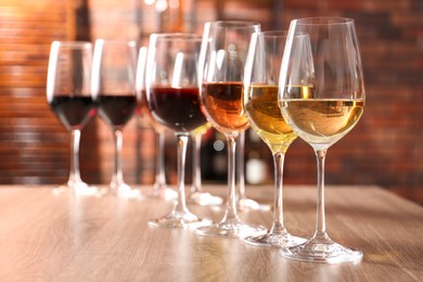 Different tasty wines in glasses on wooden table, space for text