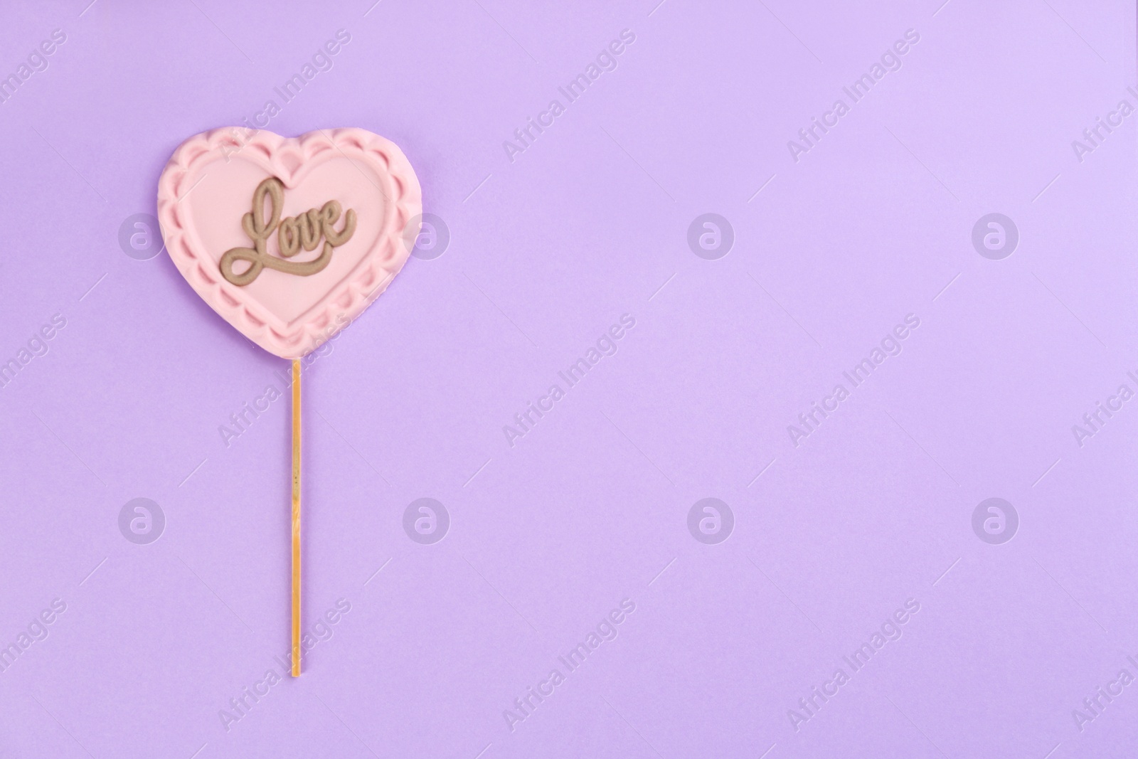 Photo of Chocolate heart shaped lollipop with word Love on light lilac background, top view. Space for text