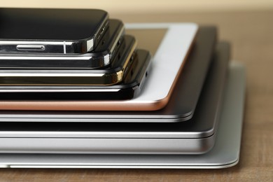 Photo of Stack of electronic devices on wooden table, closeup