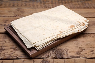 Photo of Board with delicious Armenian lavash on wooden table
