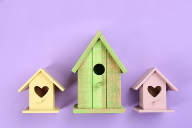 Photo of Collection of handmade bird houses on violet background, flat lay